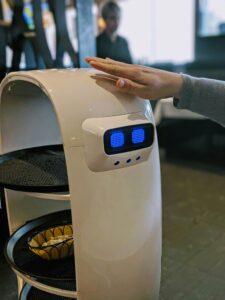 A robotic server interacting with a person in a Toronto restaurant, highlighting technology's role.