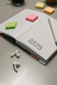 A tidy desk setup featuring a 2025 planner, sticky notes, and wireless earphones, ideal for organization.