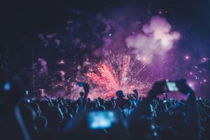 Dynamic crowd witnessing a vibrant fireworks display at a night festival, capturing the energy and joy of the event.