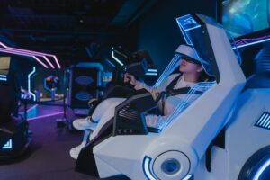 A woman enjoying a virtual reality ride in a futuristic, neon-lit arcade setting.