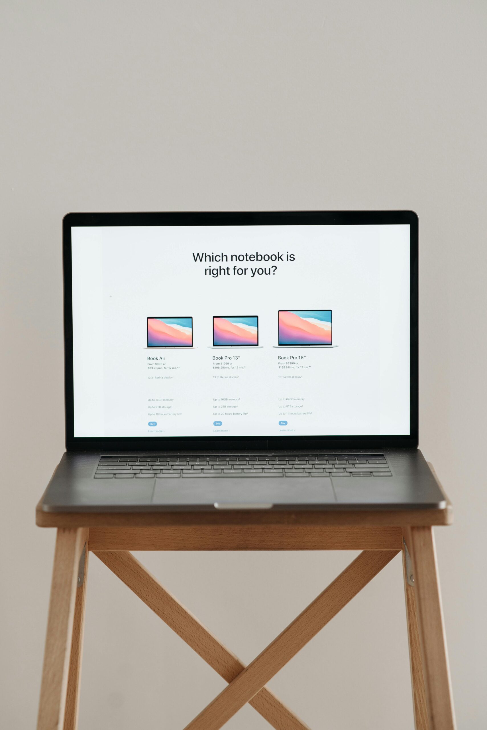 Laptop on a wooden stand with screen showing notebook comparison.