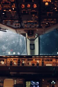 Close-up view of an aircraft cockpit's illuminated controls and instruments at night.