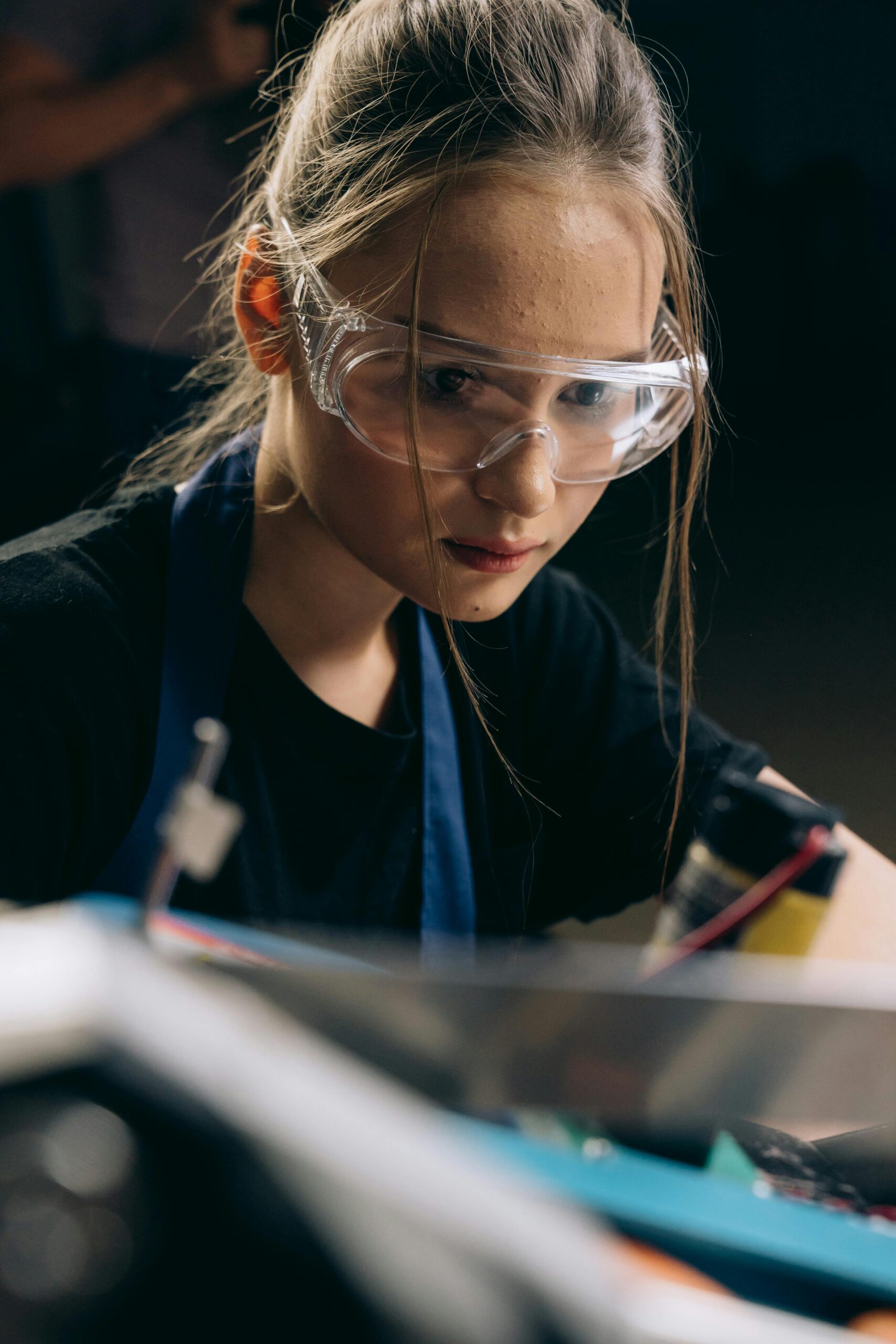 Focused young female engineer wearing safety glasses working on a project.